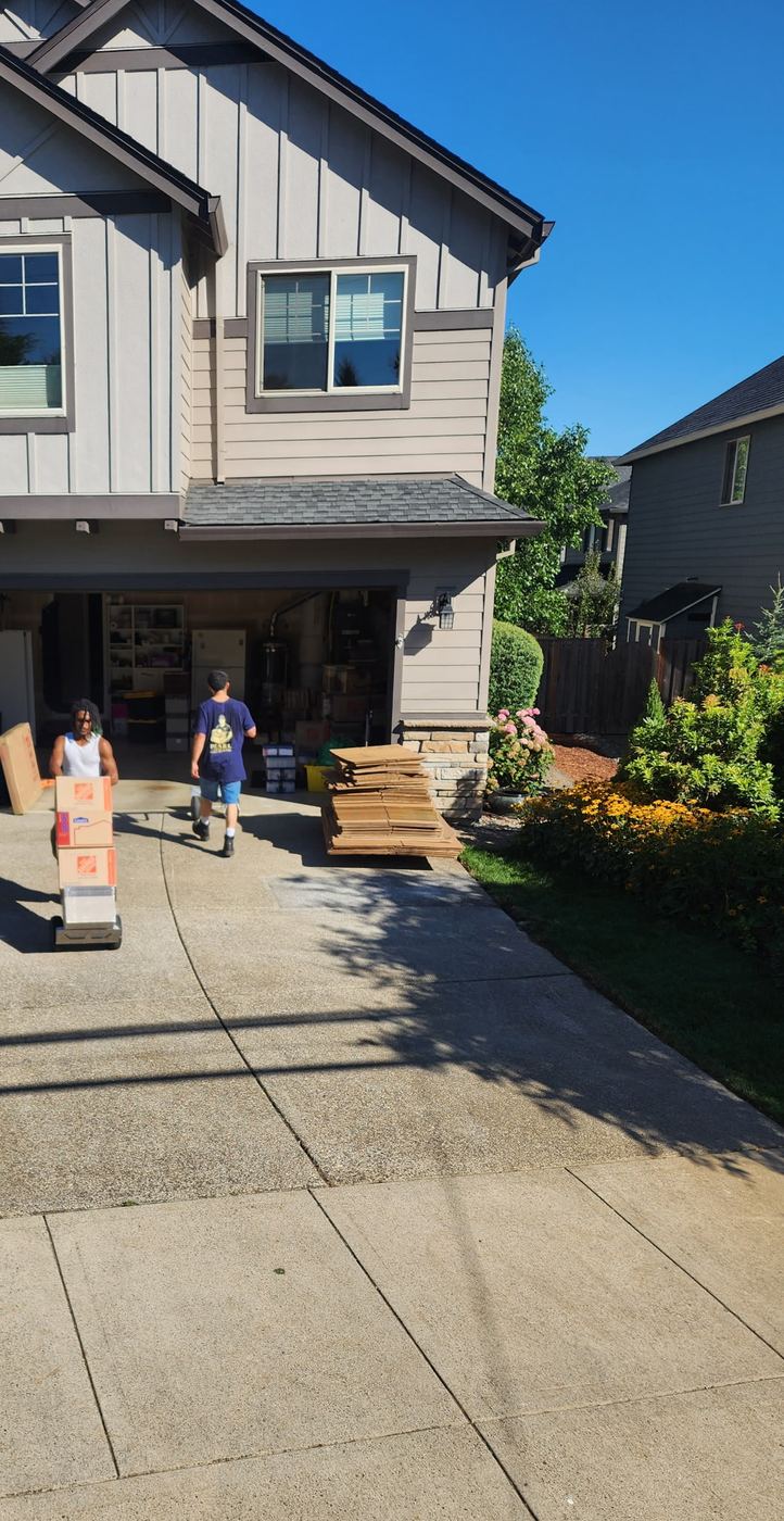 Pearl Movers crew carrying boxes down a residential driveway